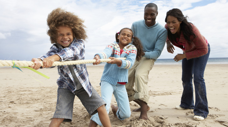 Family playing tug of war on the beach